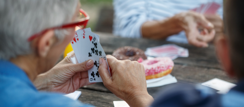 Adults gathered around a table playing Canasta during a social card game program at Worth Township.
