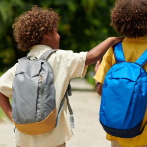 Two students wearing backpacks walk together outdoors, representing the Worth Township 2026 Backpack Giveaway for Kindergarten through 12th grade students.