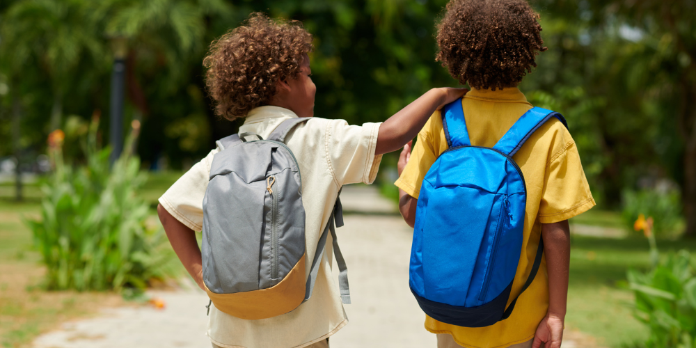 Two students wearing backpacks walk together outdoors, representing the Worth Township 2026 Backpack Giveaway for Kindergarten through 12th grade students.