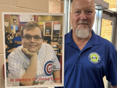 Worth Township employee stands beside a memorial photo of Jimmy Esch wearing a Chicago Cubs jersey during the Jimmy Esch Memorial Blood Drive.